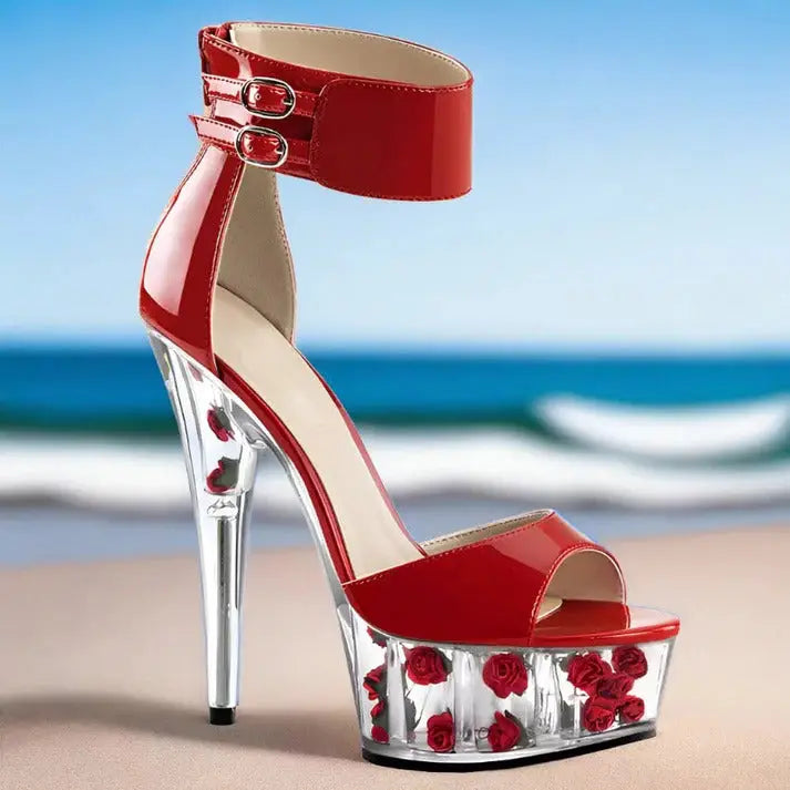 Red high-heeled platform sandal with ankle strap and clear base containing red roses.