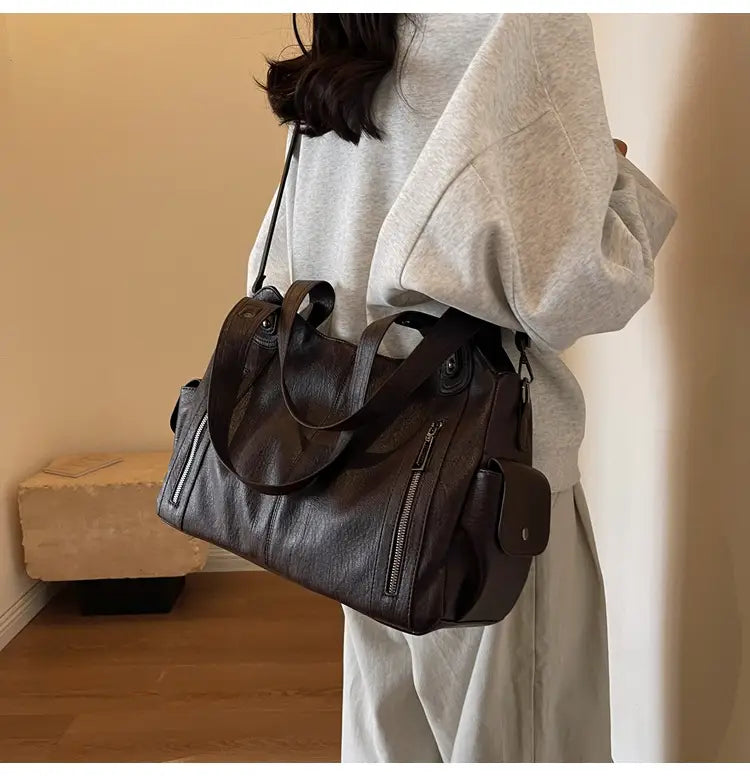 Sac messager de voyage en cuir marron foncé pour dames avec plusieurs compartiments et fermeture éclair.