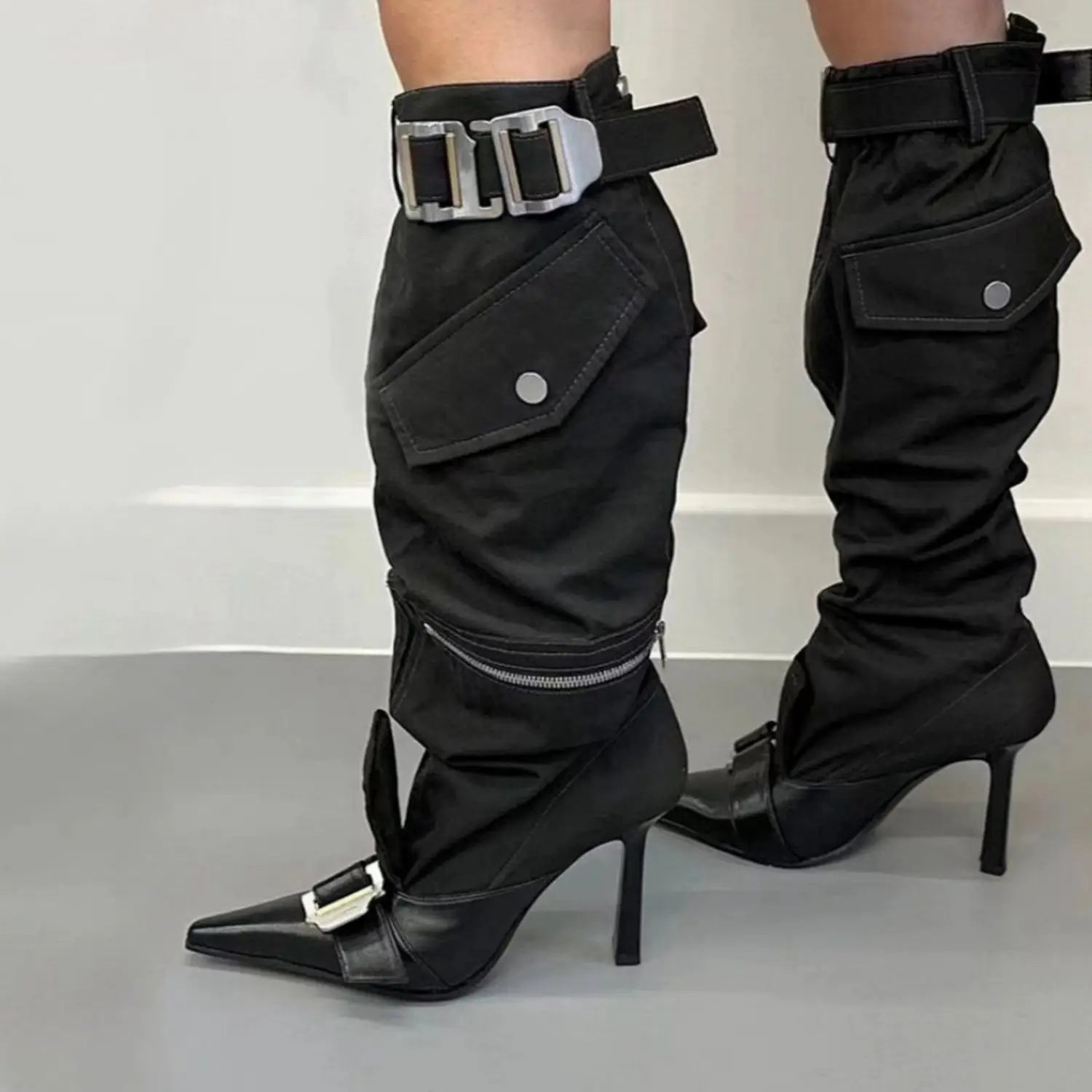 Black high heel pointed toe knee boots with cargo pockets and silver buckles.