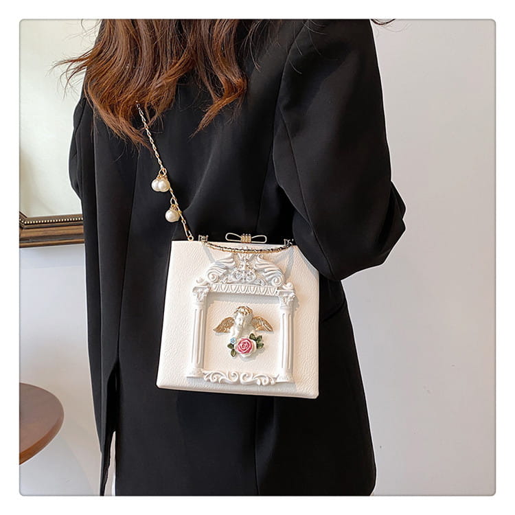 Stylish white ornate handbag featuring angel motif and bow clasp for a unique shoulder chain bag.