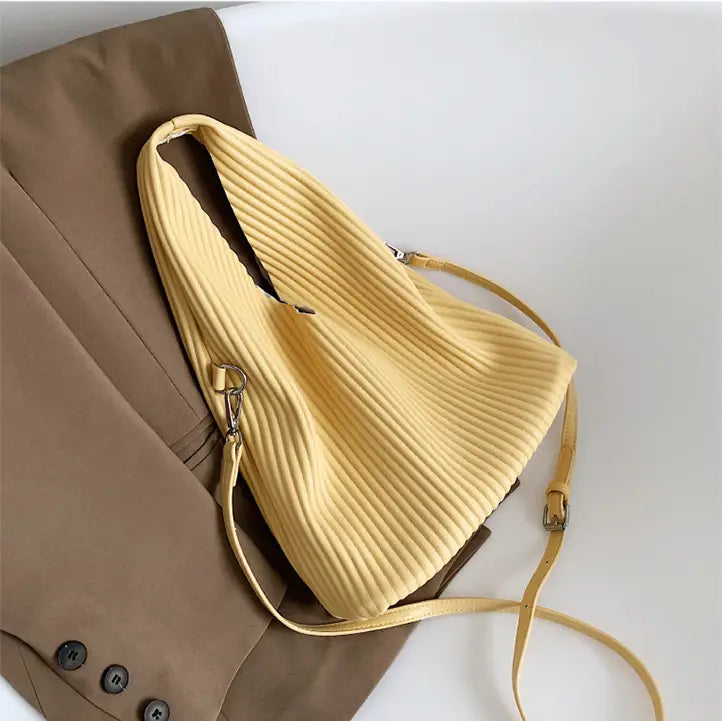 Pale yellow pleated handbag with strap, perfect for a women’s niche fashionable look.