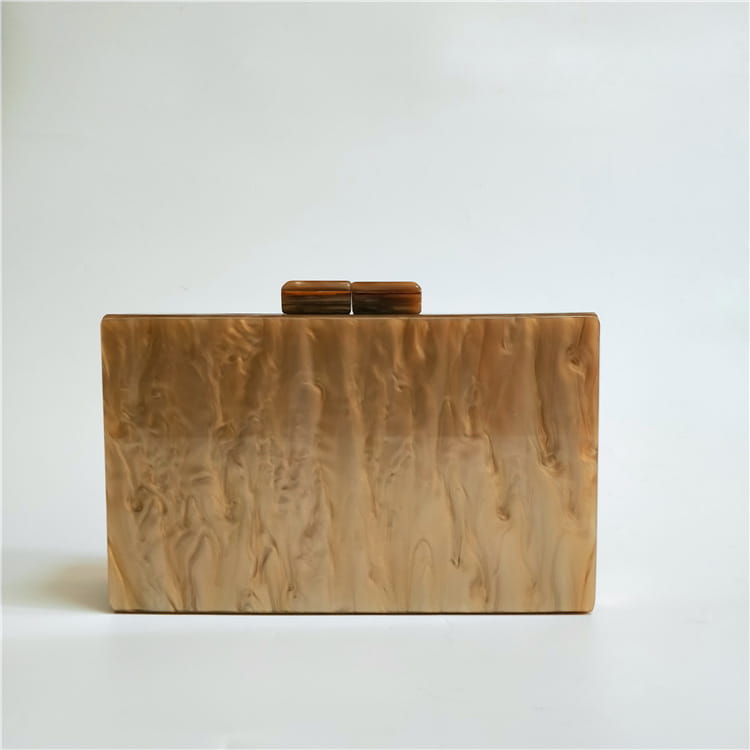 Rectangular beige acrylic clutch with brown clasp, featuring Art Deco geometric pattern.