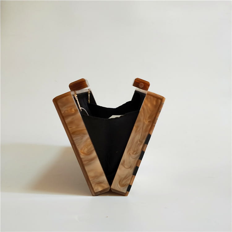 Wooden slingshot with black elastic band next to Art Deco Geometric Pattern Acrylic Clutch.