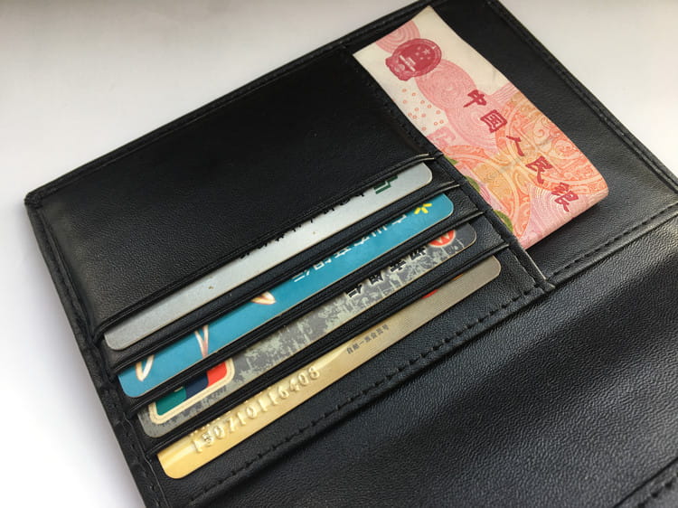 Black leather wallet with credit cards and cash, a must-have travel essential with RFID protection.