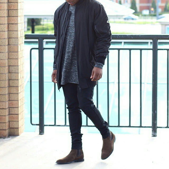 Stylish casual look with navy bomber jacket, gray shirt, black jeans, and suede pointed toe high-top Chelsea boots.