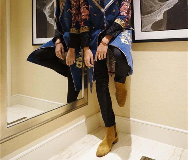 Denim jacket with colorful patches beside stylish suede pointed toe high-top Chelsea boots.