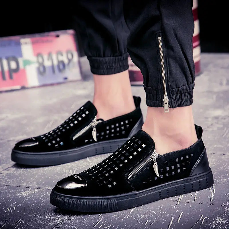 Black studded slip-on sneakers with zippers and patent toe cap for bold British style.