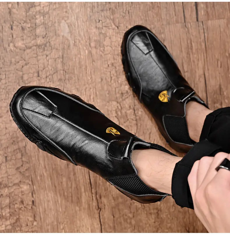 Black leather slip-on shoes with mesh panels and gold accents, perfect warm men’s casual shoes.