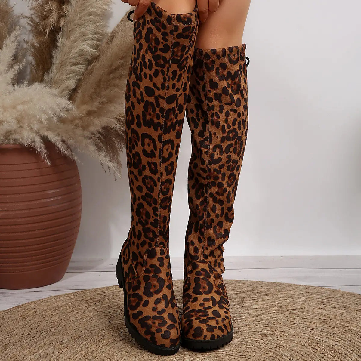 Knee-high leopard print boots with lace-up back and chunky heels for stylish looks.