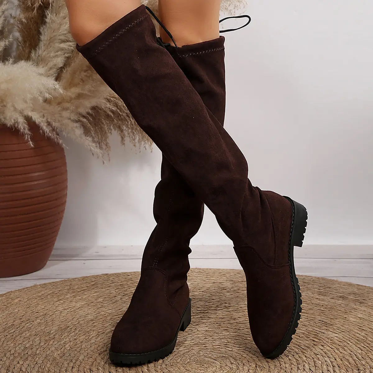 Dark brown suede knee boots with lace-up detail and flat sole for a chic look.