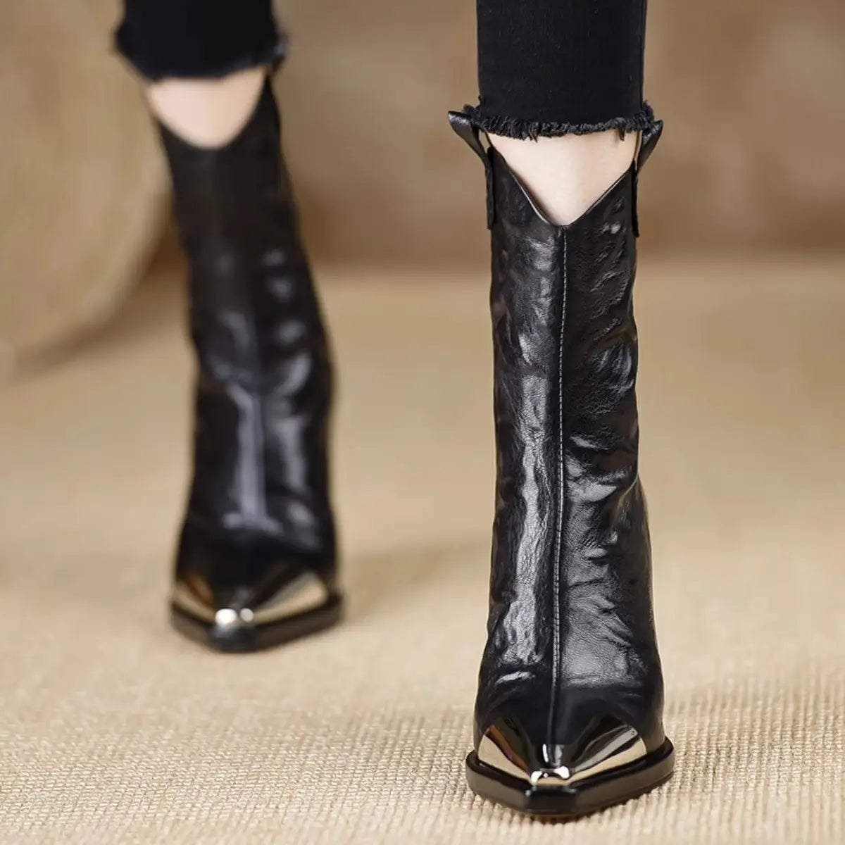 Black leather retro mid-calf boots with metal covered pointed-toe and frayed edges.