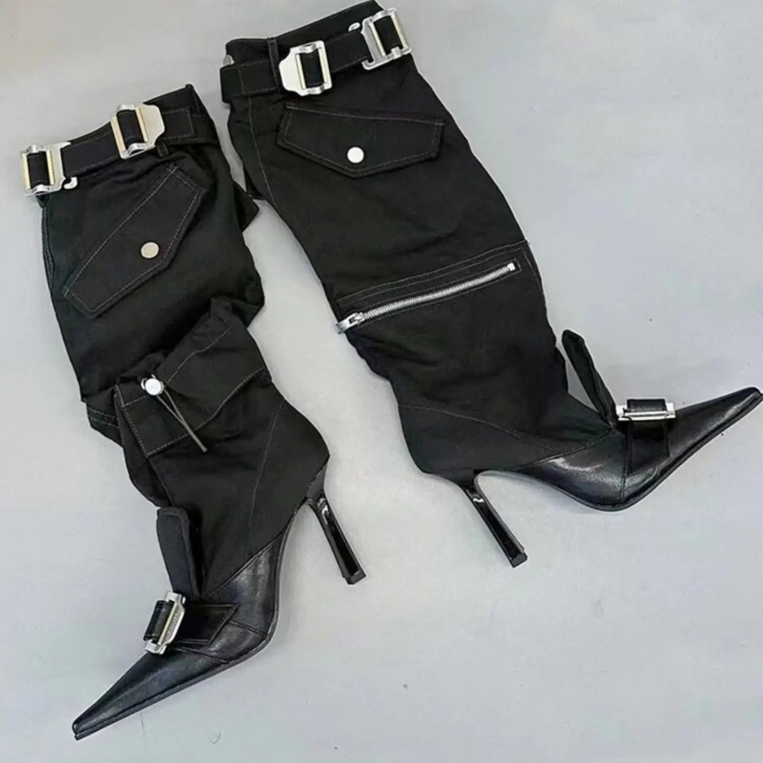 Black high-heeled pointed toe knee boots with buckles and zippers for stylish flair.