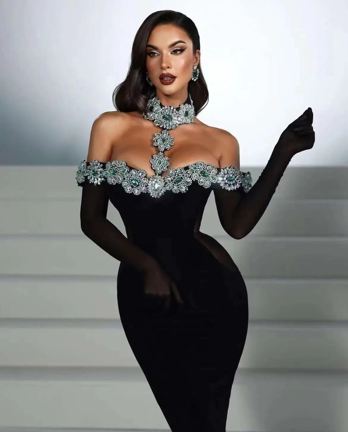 Elegant black evening gown featuring crystal-embellished neckline and sheer sleeves.