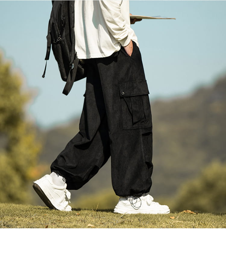 Black corduroy cargo pants with pockets and white sneakers for trendy casual style.