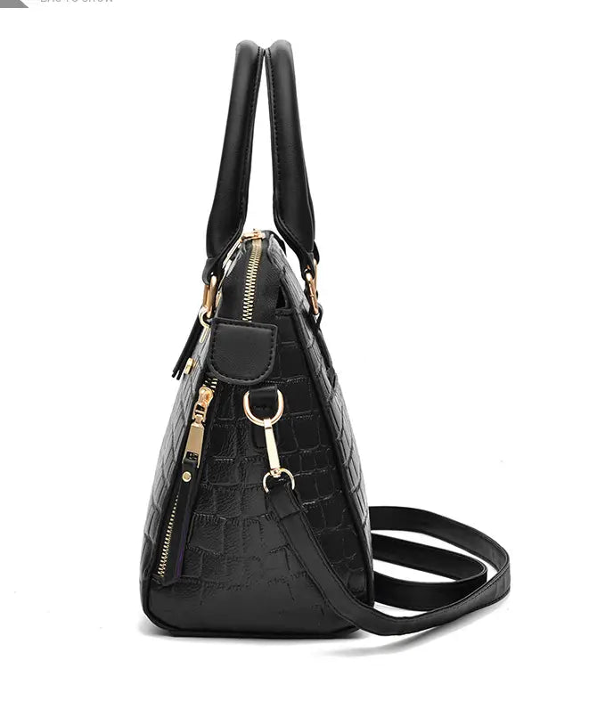 Black crocodile print handbag with gold hardware, perfect as a stylish crossbody shoulder bag.