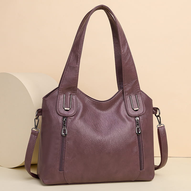 Purple leather handbag with decorative zippers and spacious interior for modern elegance.