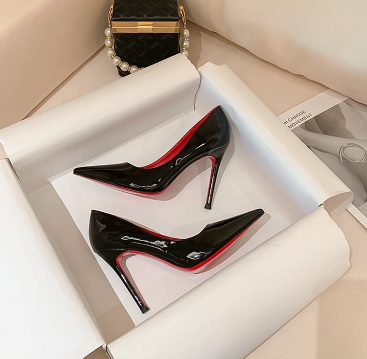 Talons hauts en cuir verni noir avec semelles rouges élégantes pour une déclaration de mode audacieuse.