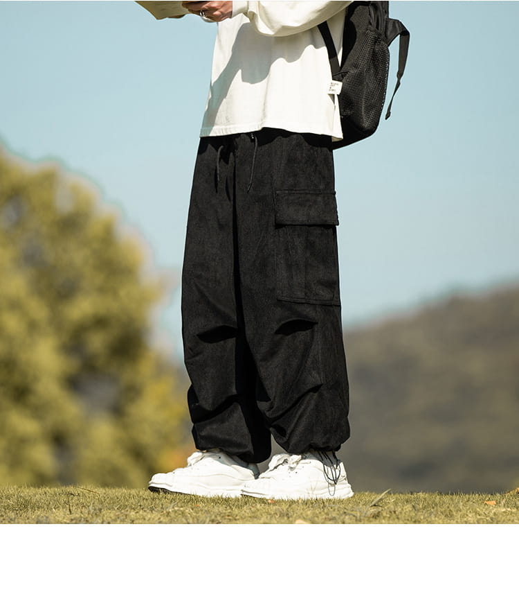 Black corduroy cargo pants with elastic cuffs styled with fresh white sneakers.