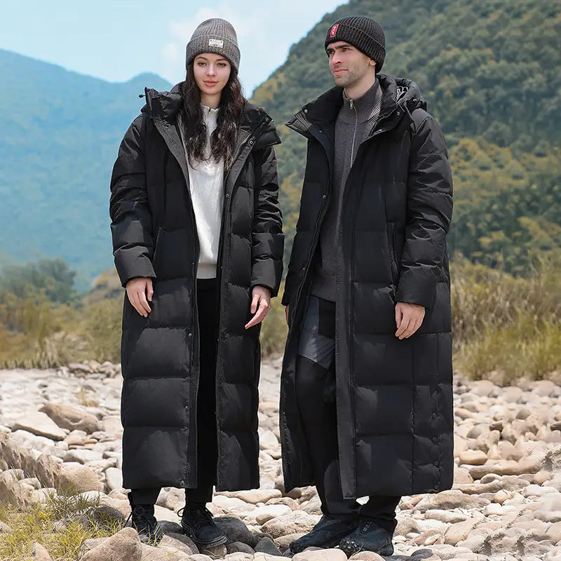 Two people in matching black luxury padded quilted long coats and beanies.