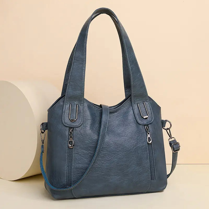 Blue leather large capacity handbag with dual handles and zippered pockets for women’s fashion.