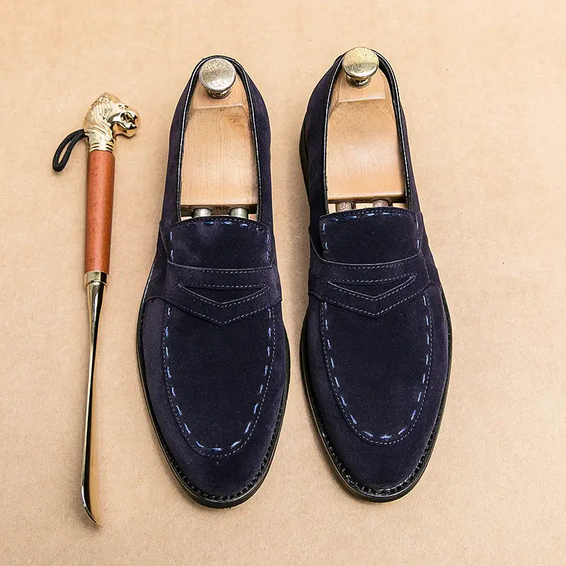 Navy blue suede penny loafers with contrast stitching for stylish pointed toe casual wear.