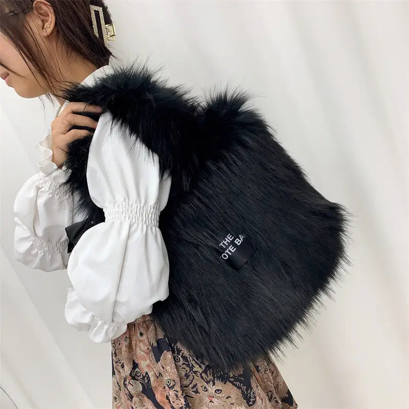 Black furry crossbody tote bag with white puffy sleeves and large capacity for style.