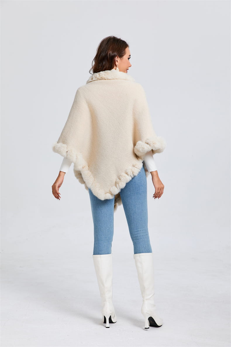 Cream-colored shawl cape poncho with faux fur collar, styled with light blue jeans and white boots.