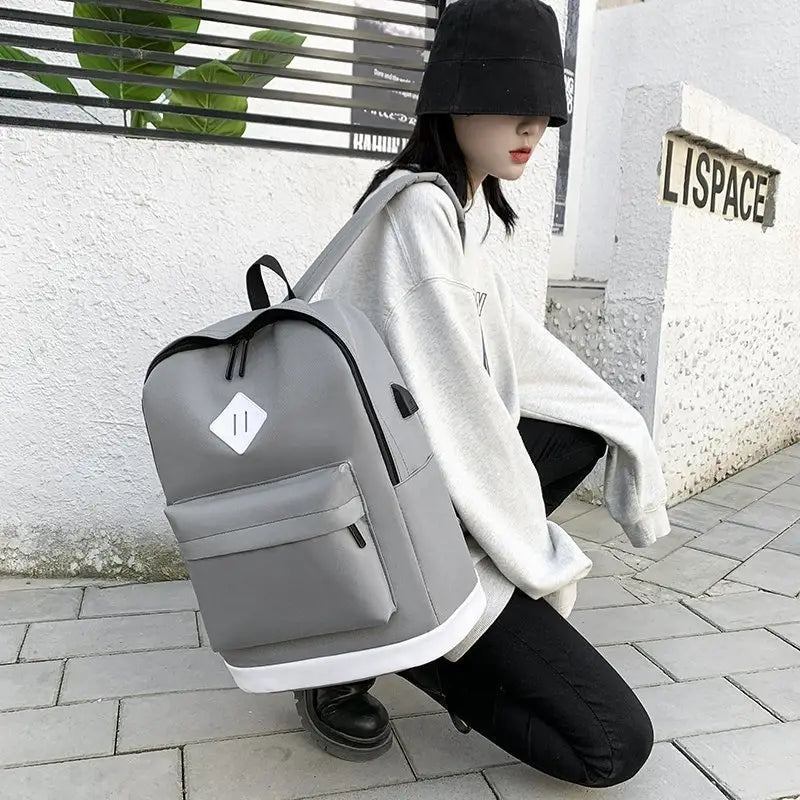 Gray large capacity USB backpack with white trim and diamond-shaped patch for travel.