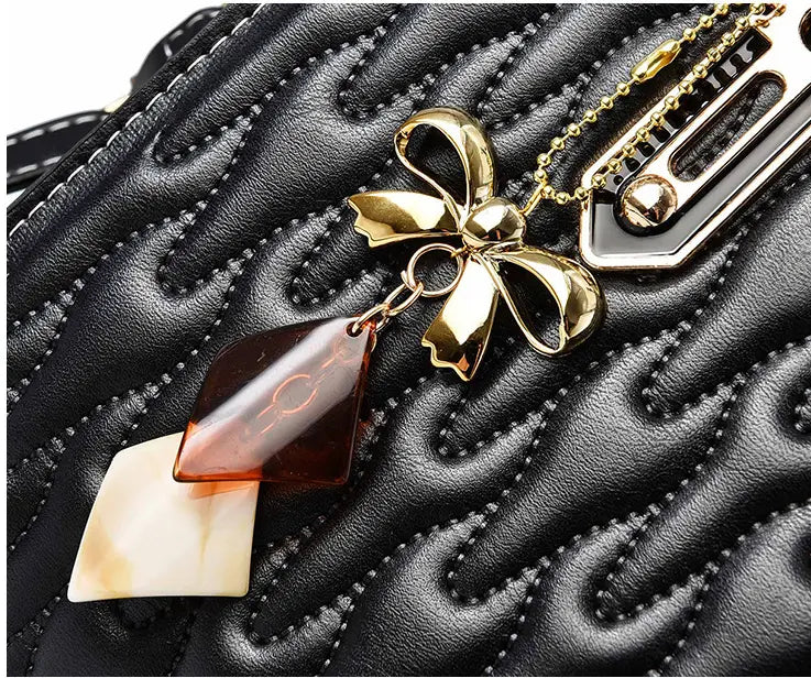 Gold bow pendant with amber and cream stones on a Pink Quilted High Capacity Fashion Handbag.