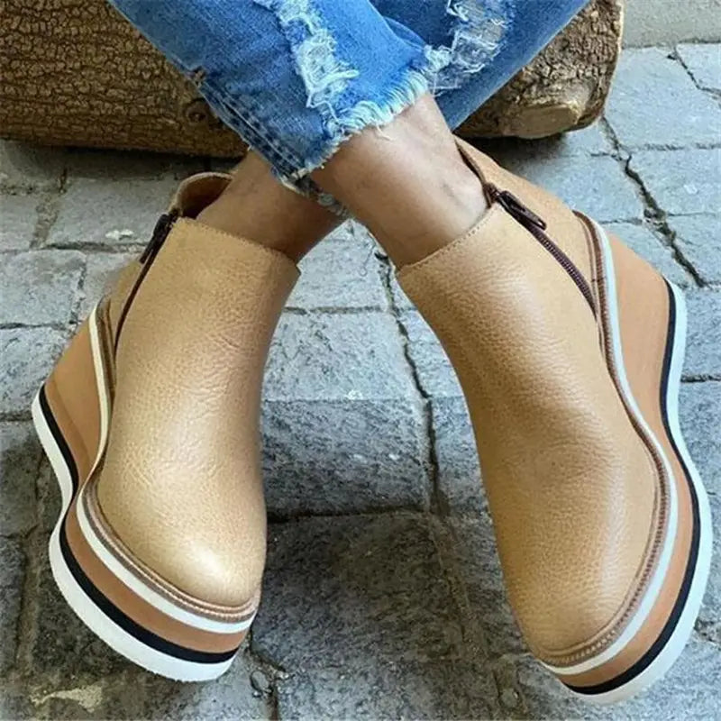 Beige platform slip-on shoes with striped soles and distressed jeans above zipper mid heel.