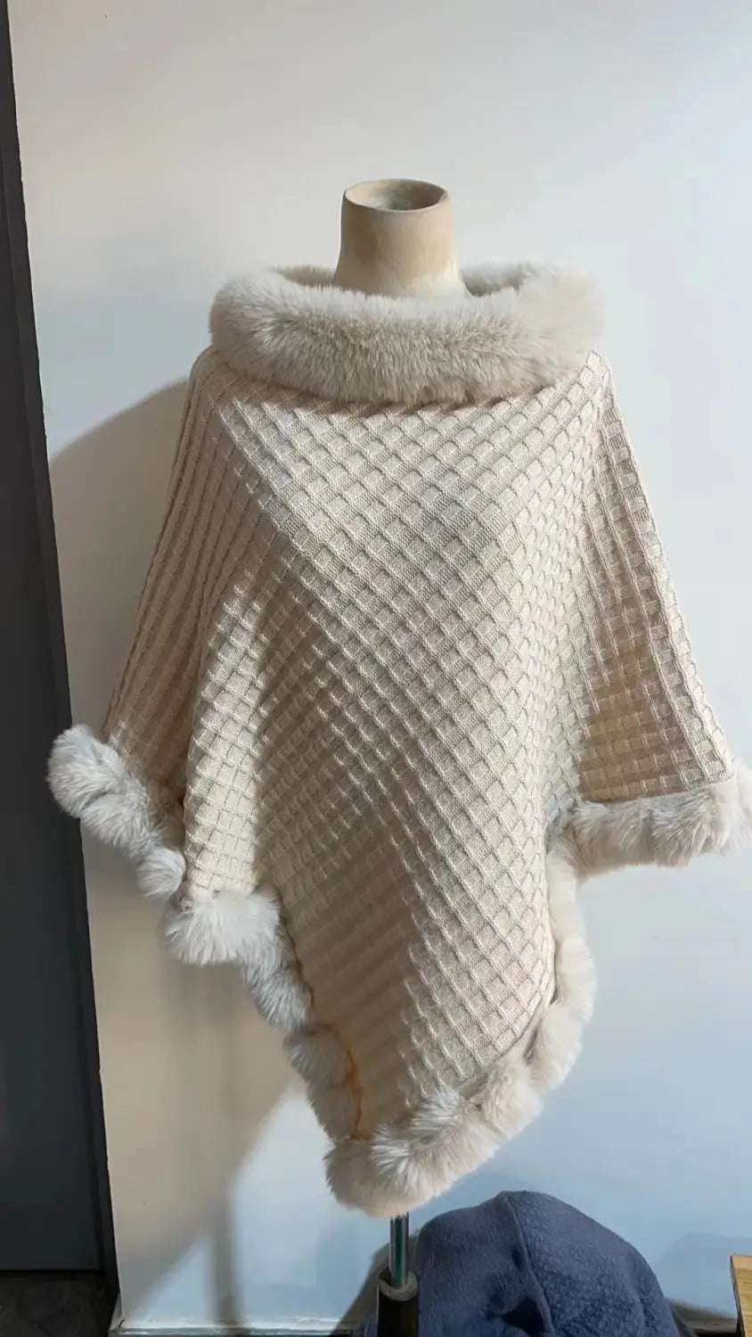 Cream-colored knit poncho with faux fur collar stylishly displayed on a mannequin.