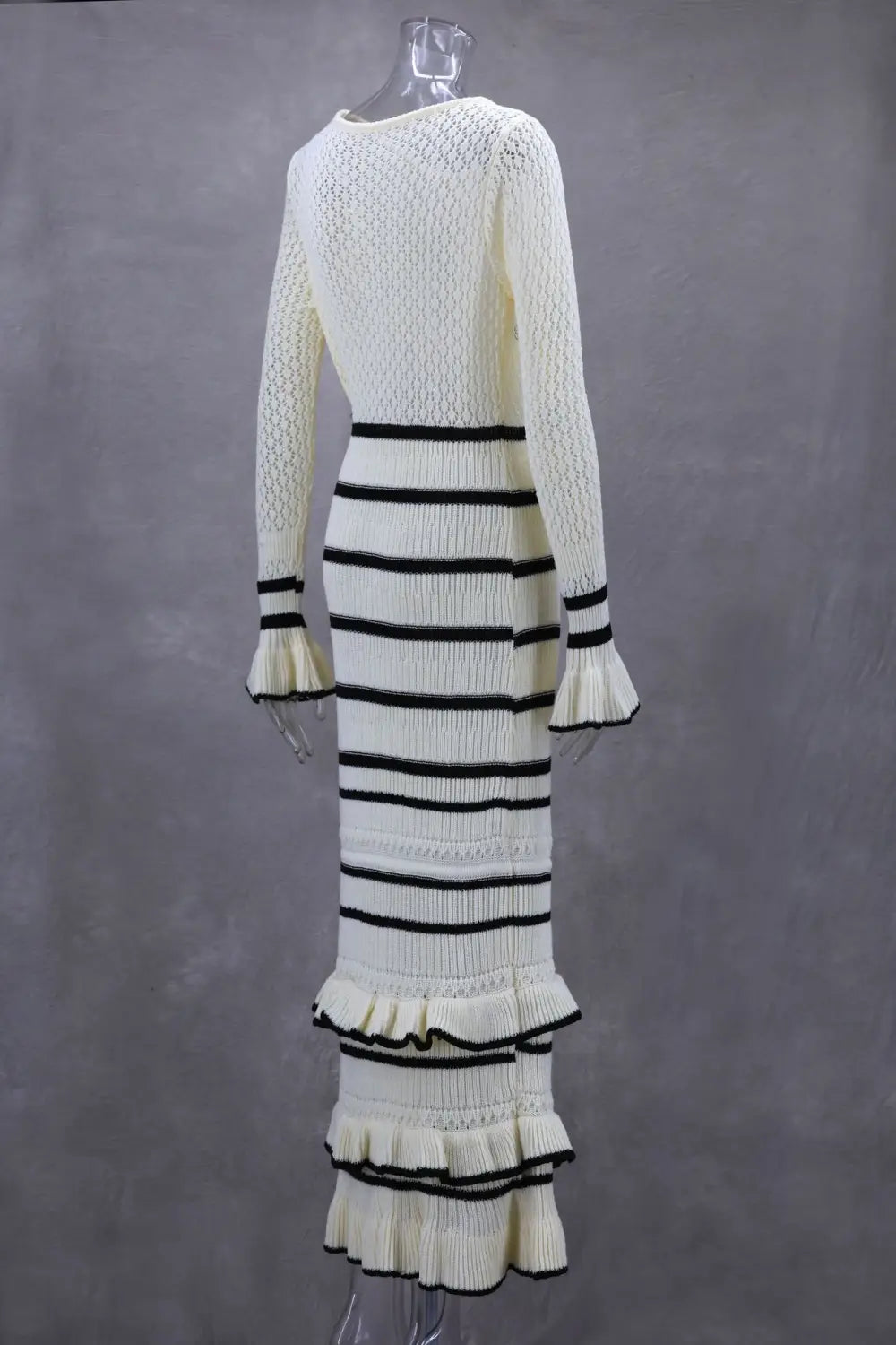 Cream-colored ladies knitted dress with black stripes and ruffled tiers for stylish flair.