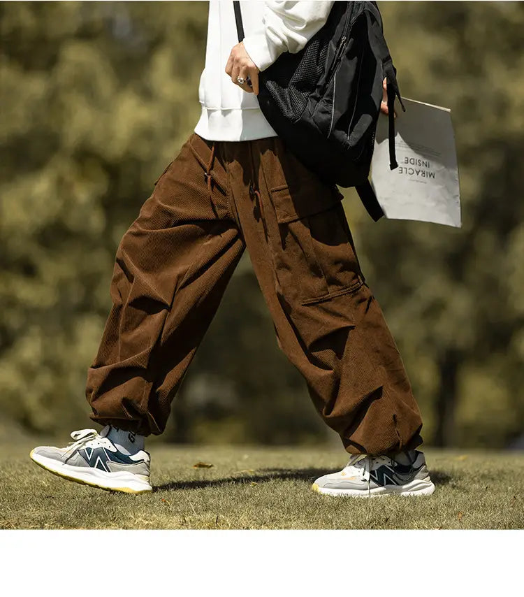 Brown corduroy cargo pants with elastic cuffs paired with gray sneakers for casual style.