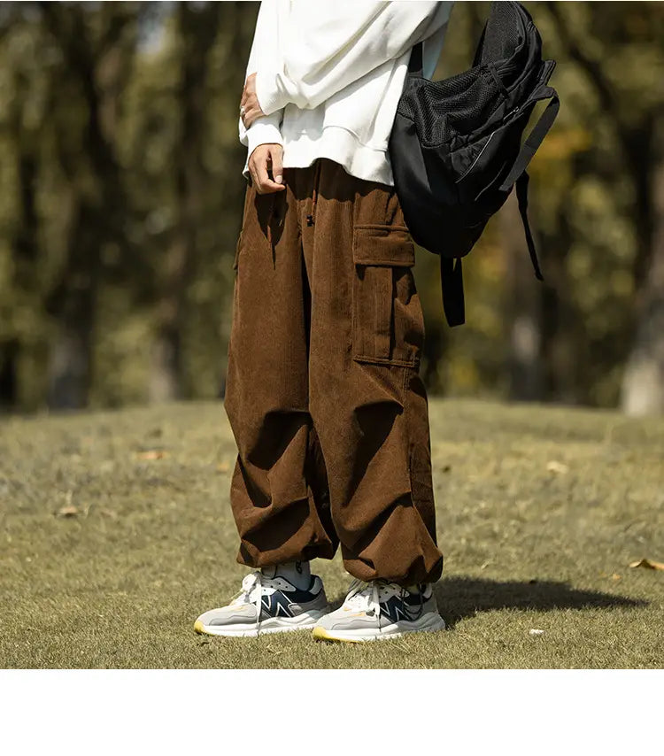 Brown corduroy cargo pants with pockets, paired with cool white sneakers for casual style.