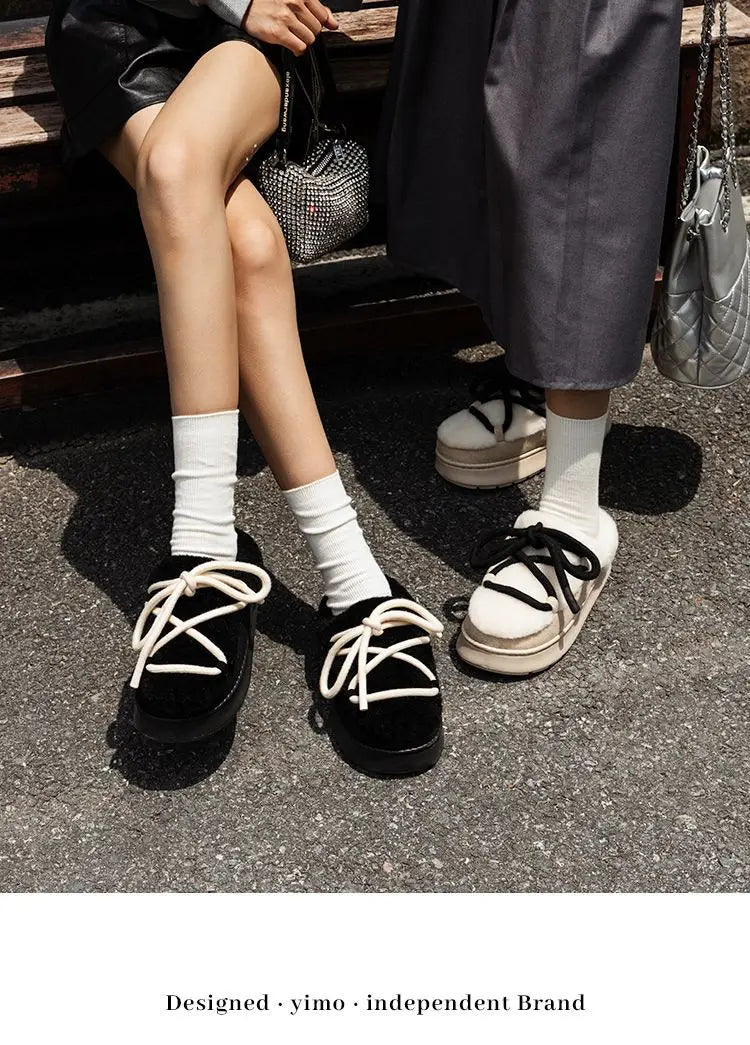 Black and white suede platform closed-toe fur slippers with laces and white socks.