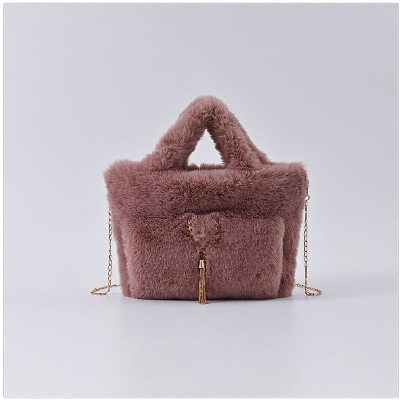 Sac à main en imitation fourrure rose poudré avec une sangle en chaîne dorée et des détails en forme de houppe.