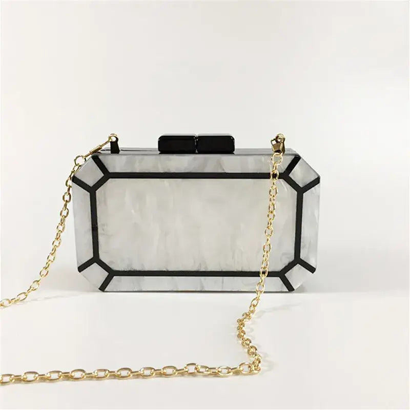 Clear acrylic clutch purse with black trim and gold chain for Art Deco design lovers.