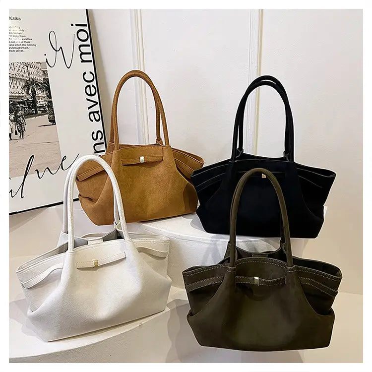 Quatre sacs fourre-tout élégants en daim, de couleur marron, noire, blanche et olive, avec des poignées incurvées.