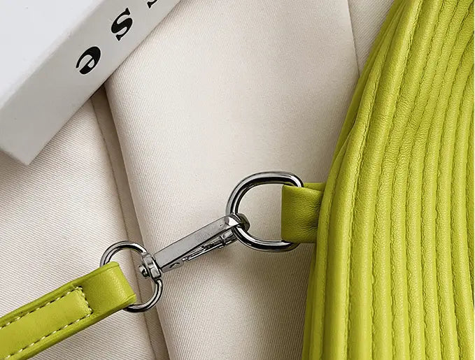 Metal clasp on lime-green leather in a stylish textured messenger bag for women’s niche fashionable look.