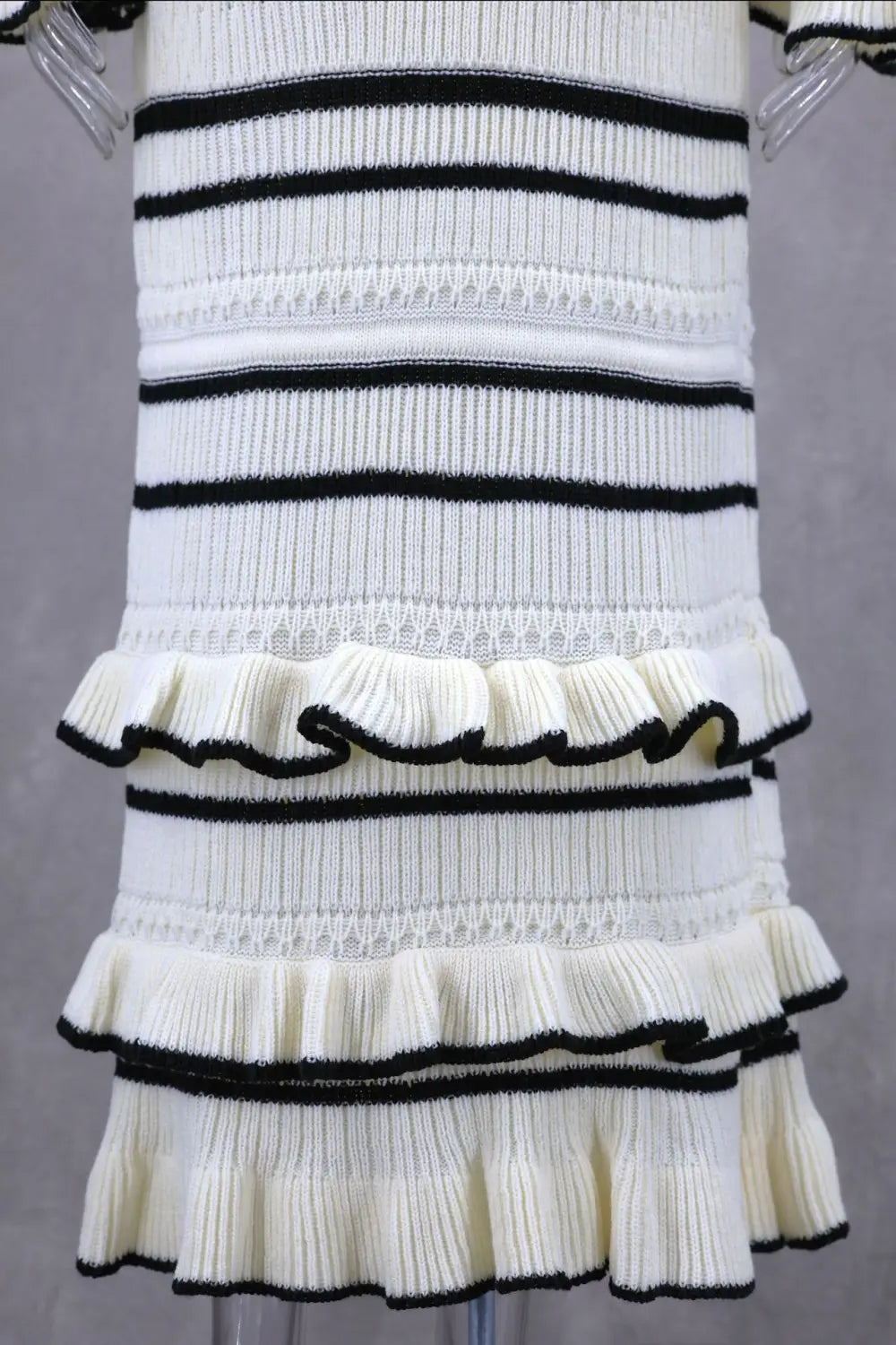 Elegant ladies knitted dress with black stripes and ruffled tiers for a stylish look.