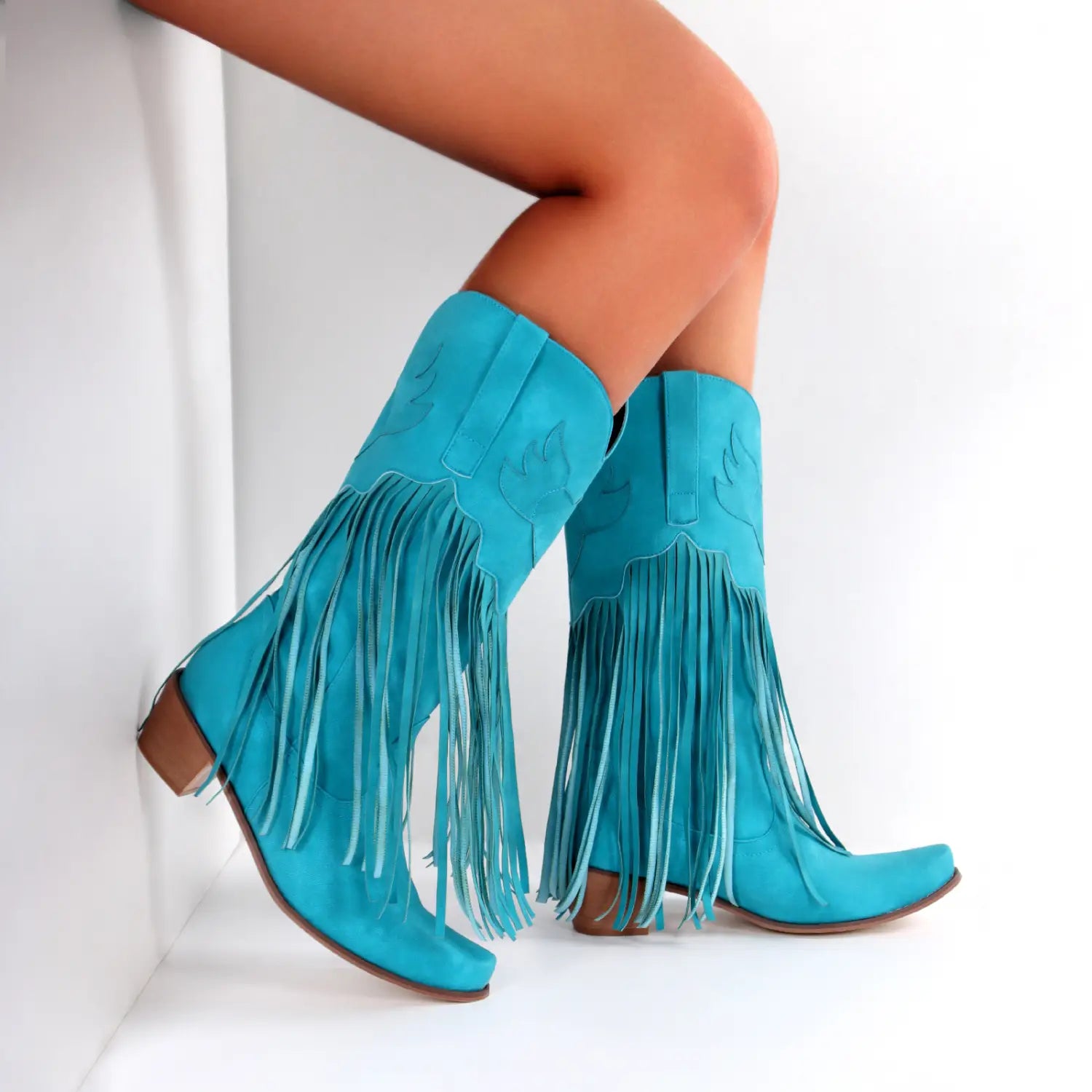 Turquoise suede womens cowboy boots with long tassel details and wooden heels.