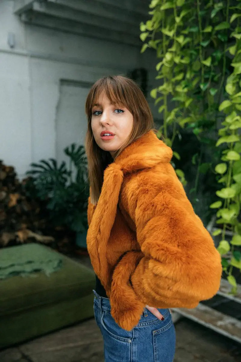 Orange faux fur cropped jacket with blue jeans for a cozy, chic look with wine red vibes.