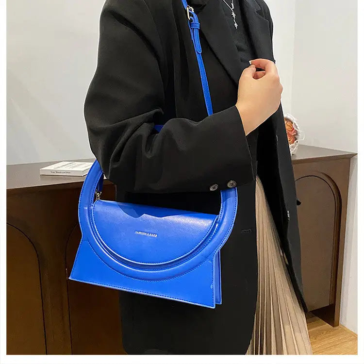 Bright blue designer handbag versatile with curved top handle and shoulder crossbody strap