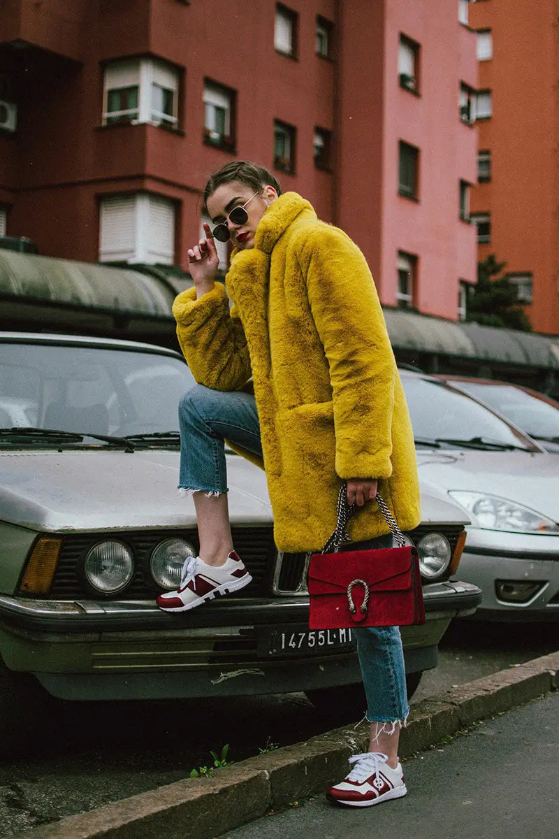 Bright yellow fur coat with jeans and red sneakers, perfect for cozy chic vibes.