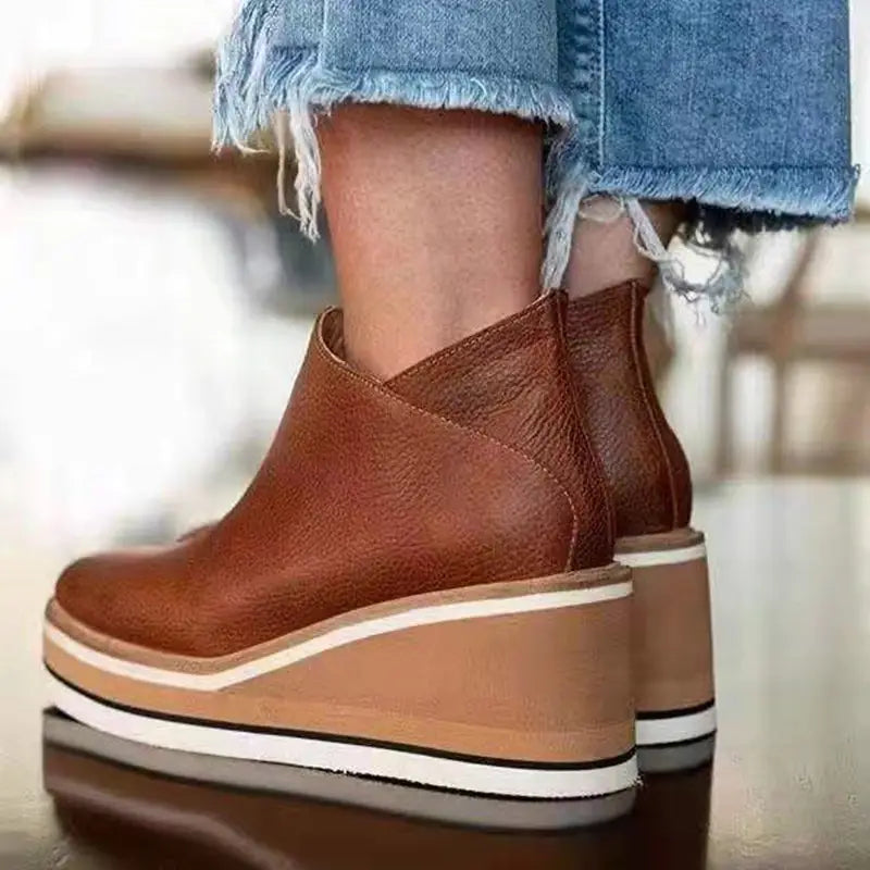 Brown leather platform ankle boots with zipper mid heel and striped wedge heel.