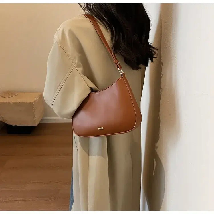 Brown leather shoulder bag crossbody with a stylish curved silhouette for luxury vibes.