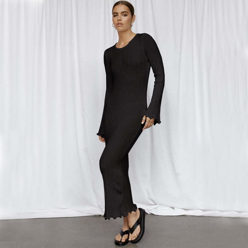 Long black knit dress with flared sleeves and scalloped hem.