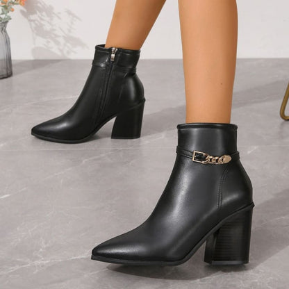 Black leather ankle boots with pointed toes, chunky heels, and gold chain accents.