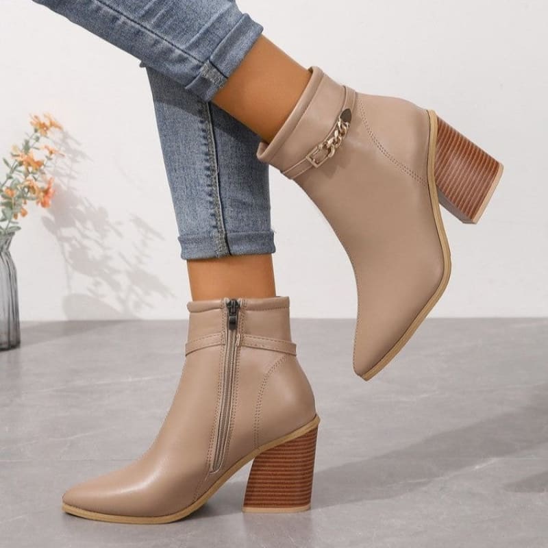 Beige leather ankle boots with chunky wooden heels and decorative chain detail.