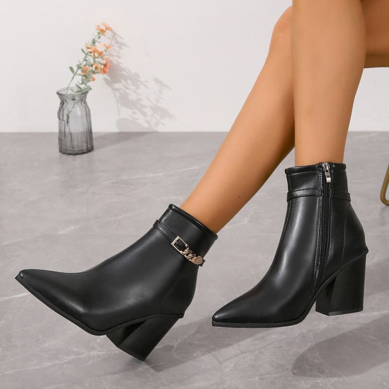 Black leather ankle boots with pointed toes, block heels, and decorative gold buckle straps.